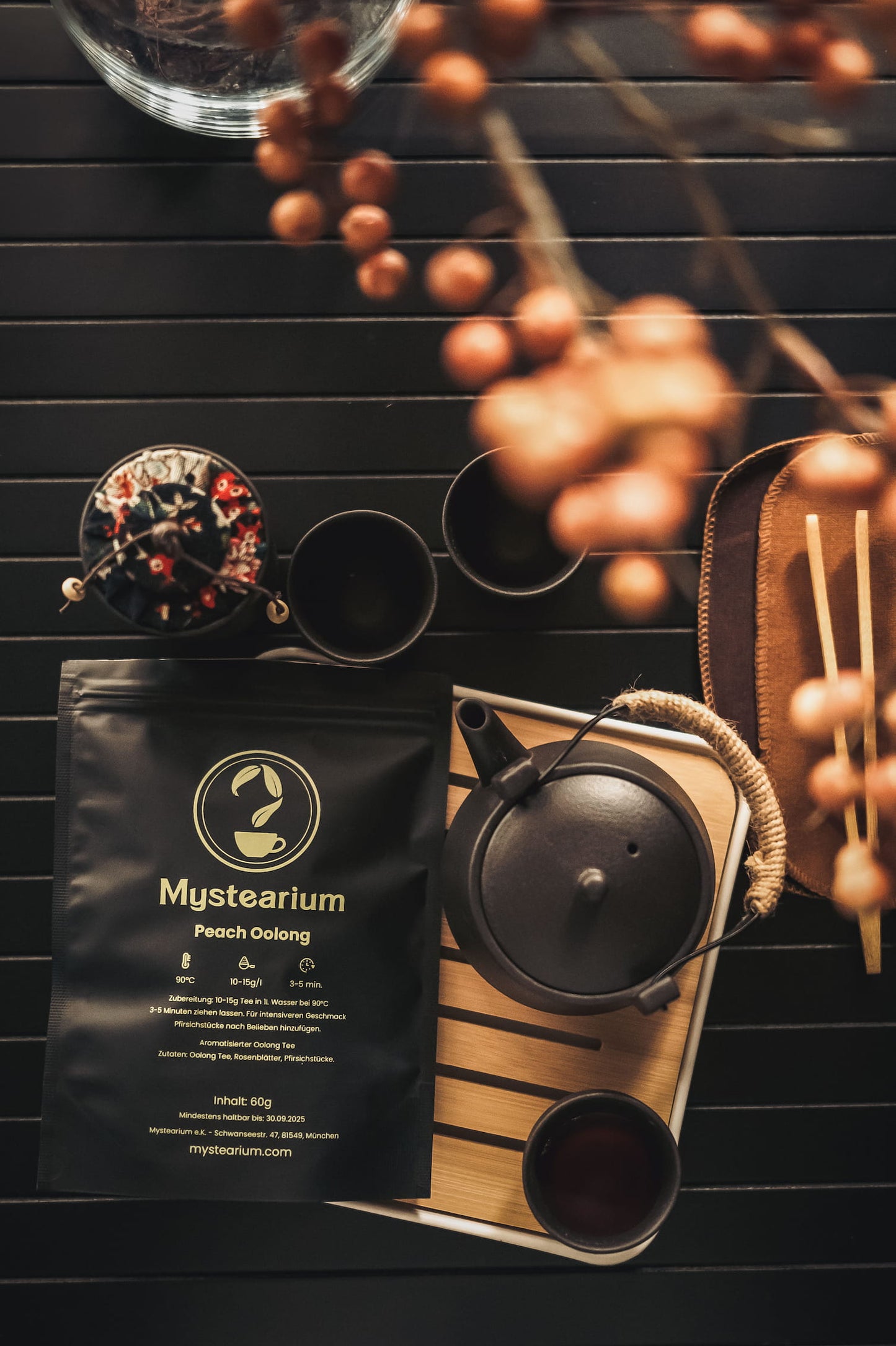 Mystearium peach oolong tea packaging with a black teapot and a cup on awooden tray.